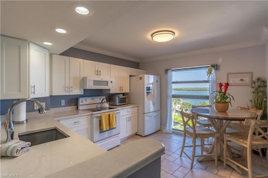 Kitchen with white appliances, sink, light tile pa
