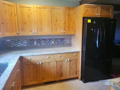 Kitchen with freestanding refrigerator, backsplash, and light stone counters