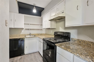 Kitchen with granite counters, black appliances, white cabinetry, and under cabinet range hood