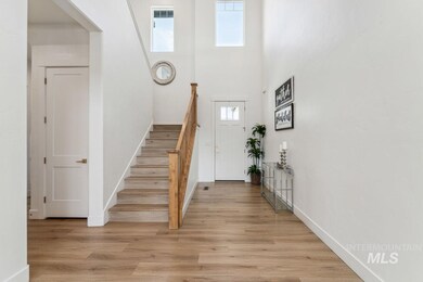 Foyer entrance featuring light wood-style flooring, stairs, and a towering ceiling