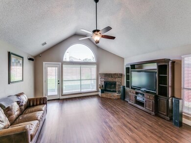 Living room featuring wood-style flooring, a brick fireplace, lofted ceiling, and ceiling fan