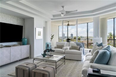 Living area featuring a raised ceiling, a ceiling fan, a view of city, tile patterned flooring, and a wall of windows
