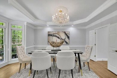Dining space featuring wood finished floors, a notable chandelier, a raised ceiling, and crown molding