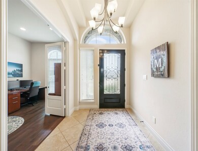A large chandelier enhances the entry with its beautiful front door with decorative iron grill and arched window.