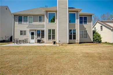 Back of property with a lawn, a shingled roof, and a patio
