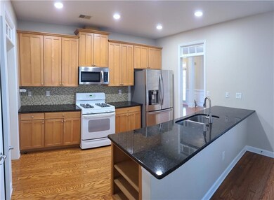 Kitchen with sink, kitchen peninsula, appliances with stainless steel finishes, and light hardwood / wood-style flooring