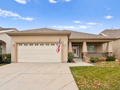View of front of home featuring stucco siding, covered porch, a shingled roof, and a front yard