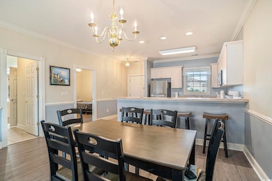 Dining area with a chandelier, crown molding, light wood-style floors, baseboards, and recessed lighting