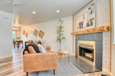 Living room with a fireplace, wood finished floors, recessed lighting, and baseboards
