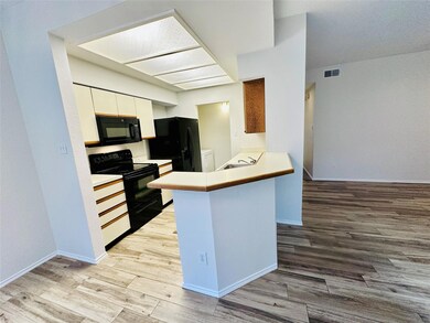 Kitchen featuring black appliances, a peninsula, light wood-type flooring, and white cabinets