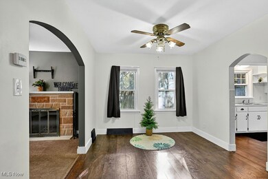 Dining room with arched walkways & dark wood-style floors, and ceiling fan