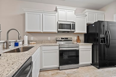 Kitchen featuring white cabinetry, sink, light sto