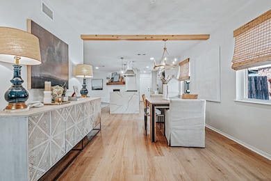 Dining room with light wood finished floors, a chandelier, and beam ceiling