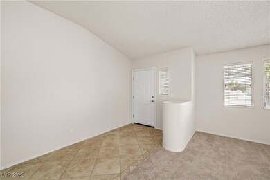 Empty room with a textured ceiling, light tile pat