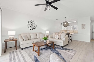 Living area with light wood-type flooring, ornamental molding, and ceiling fan