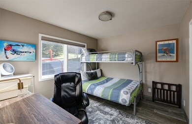 Bedroom with wood finished floors and an office ar