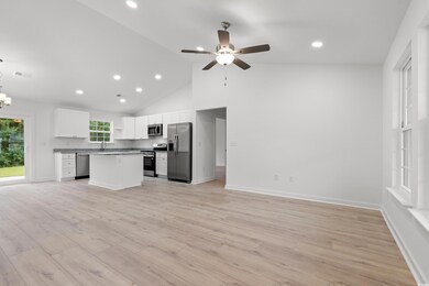 Kitchen featuring open floor plan, white cabinets, light wood-type flooring, open shelves, and a center island