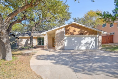 Mid-century home with a garage, driveway, and bri