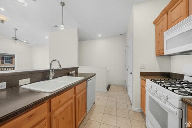 Kitchen with white appliances, decorative light fixtures, light tile patterned flooring, recessed lighting, and a ceiling fan