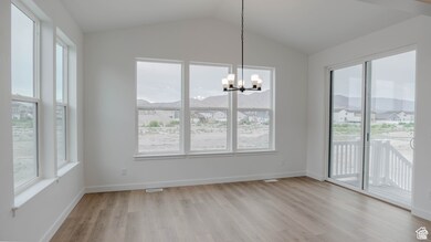 Unfurnished dining area featuring light wood finished floors, a chandelier, a mountain view, and vaulted ceiling