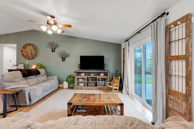 Living room featuring lofted ceiling, wood finished floors, and ceiling fan