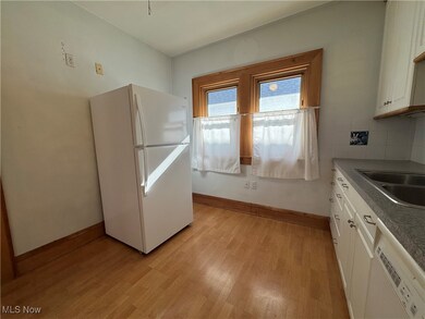Kitchen with sink, white cabinetry, tasteful backsplash, light wood-type flooring, and white appliances