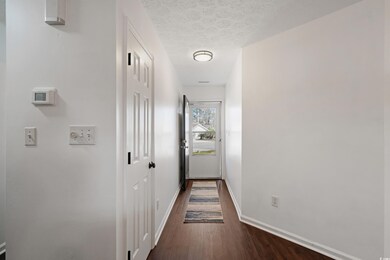Hallway featuring dark wood-type flooring, baseboa