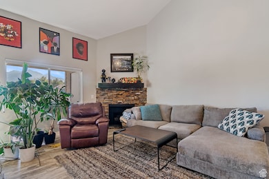 Living area with wood finished floors, a stone fireplace, and high vaulted ceiling