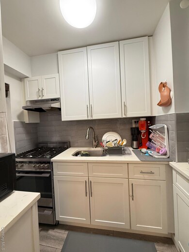 Kitchen featuring range, white cabinets, and extractor fan