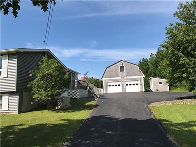 Paved driveway with view of shingled...