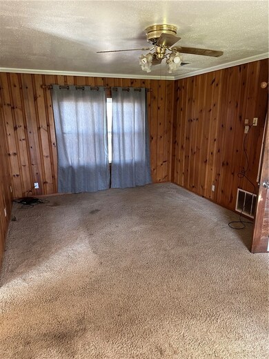 Spare room with carpet, crown molding, a textured ceiling, and wooden walls