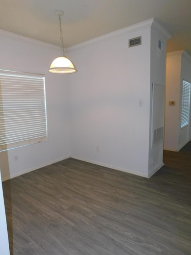 Spare room featuring ornamental molding and dark wood-style flooring