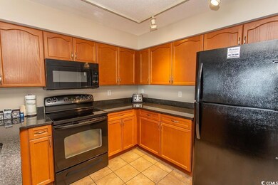 Kitchen with black appliances, light tile patterne