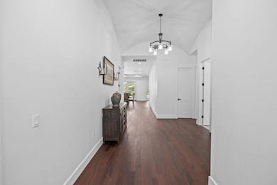 Hallway featuring a chandelier, dark wood-style f