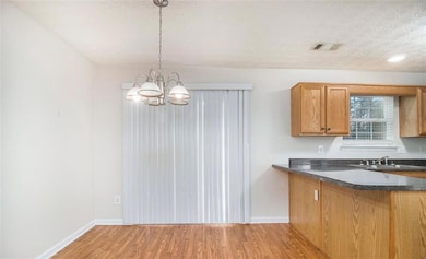 Kitchen with dark countertops, light wood-style flooring, baseboards, and a chandelier