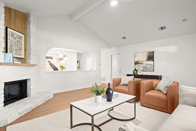 Living area featuring beam ceiling, wood finished floors, a fireplace, and high vaulted ceiling