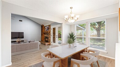 Dining space with light wood-style flooring, a textured ceiling, vaulted ceiling, a brick fireplace, and french doors