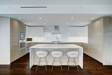 MODERN AND SLEEK KITCHEN FEATURES LARGE EAT-IN ISLAND, MARBLE COUNTERTOPS AND GAGGENAU APPLIANCES