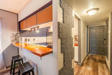 Kitchen with wood finished floors, a textured cei