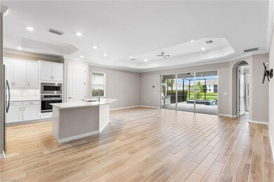 Kitchen featuring a raised ceiling, ornamental molding, open floor plan, arched walkways, and appliances with stainless steel finishes