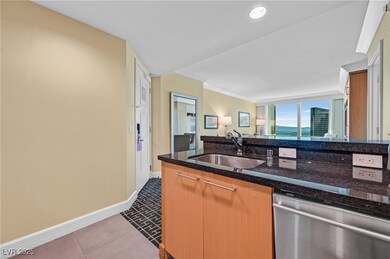 Kitchen with stainless steel dishwasher, dark stone countertops, dark tile patterned flooring, and open floor plan