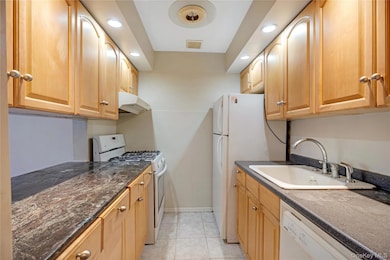 Kitchen featuring white appliances, recessed lighting, under cabinet range hood, light tile patterned flooring, and light brown cabinets