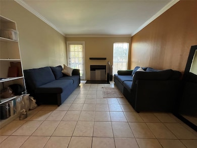 Living room featuring crown molding, light tile patterned floors, and a fireplace