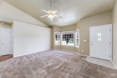 Entryway featuring carpet floors, ceiling fan, vaulted ceiling, and tile patterned flooring