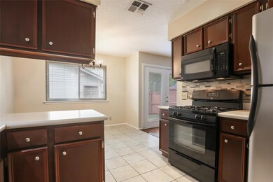 Kitchen with a textured ceiling, visible vents, l
