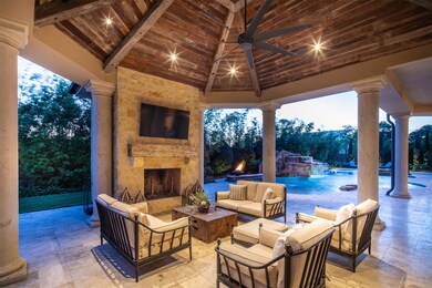 Enjoy decadent indoor-outdoor living in the stunning covered pavilion topped by an exposed beam ceiling and fan and flanked by a woodburning fireplace and full summer kitchen.