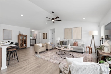 Living room with light hardwood / wood-style floors, ceiling fan, and vaulted ceiling