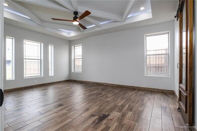 Spare room featuring ceiling fan, a barn door, a raised ceiling, and beamed ceiling