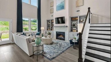 Living area featuring a towering ceiling, healthy amount of natural light, wood finished floors, a glass covered fireplace, and stairway