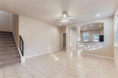 Unfurnished living room featuring light tile patterned flooring, recessed lighting, arched walkways, stairway, and ceiling fan